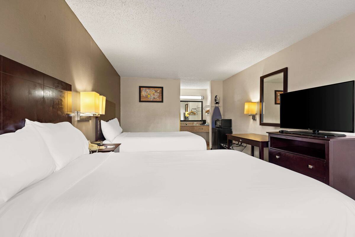 Une chambre d’hôtel avec deux lits, une télévision, un bureau et une commode.