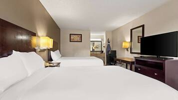 A hotel room with two beds, a TV, a desk, and a dresser.