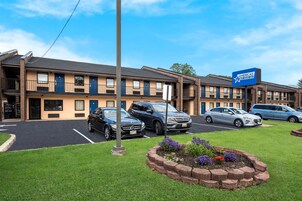 Un motel con varias habitaciones, un estacionamiento y un cartel que indica que pertenece a la red Amerisuites.