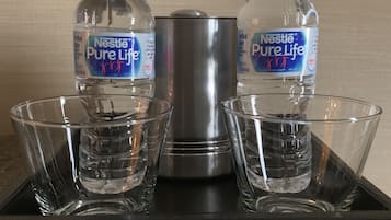 Ein Tablett mit zwei Nestle Pure Life Wasserflaschen und einem Edelstahl-Wasserhahn, dazu vier klare Gläser.