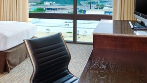 Ett hotellrum med ett stort fönster, en säng, ett skrivbord och en stol.