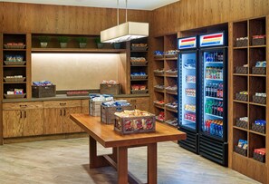 Ein Holzinnenraum mit einem Tisch, Regalen und einem mit Getränken gefüllten Kühlschrank.