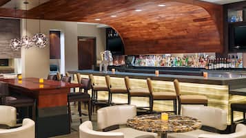A bar area with a wooden ceiling, a bar counter with a variety of bottles, and seating arrangements.