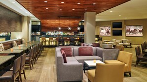 Ett rymligt loungeområde med en bar i bakgrunden, bekväma sittplatser och ett träpanelat tak.