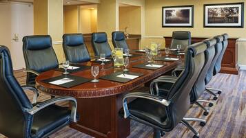 A conference room with a long table, black leather chairs, and framed pictures on the wall.