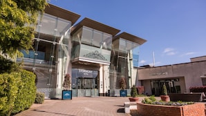A modern hotel with a glass facade, a prominent entrance, and landscaped outdoor areas.