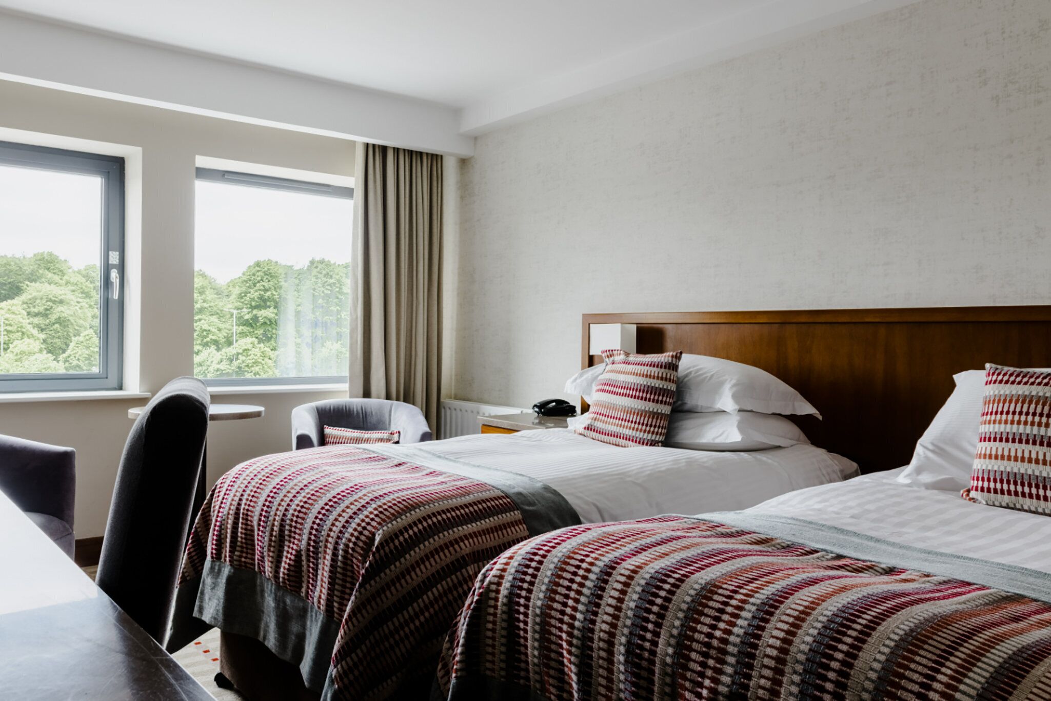 Habitación de hotel con dos camas, un escritorio y una silla.