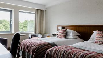 Habitación de hotel con dos camas, un escritorio y una silla.