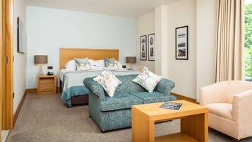 Une chambre d’hôtel avec un lit, deux canapés, une table basse et une chaise.