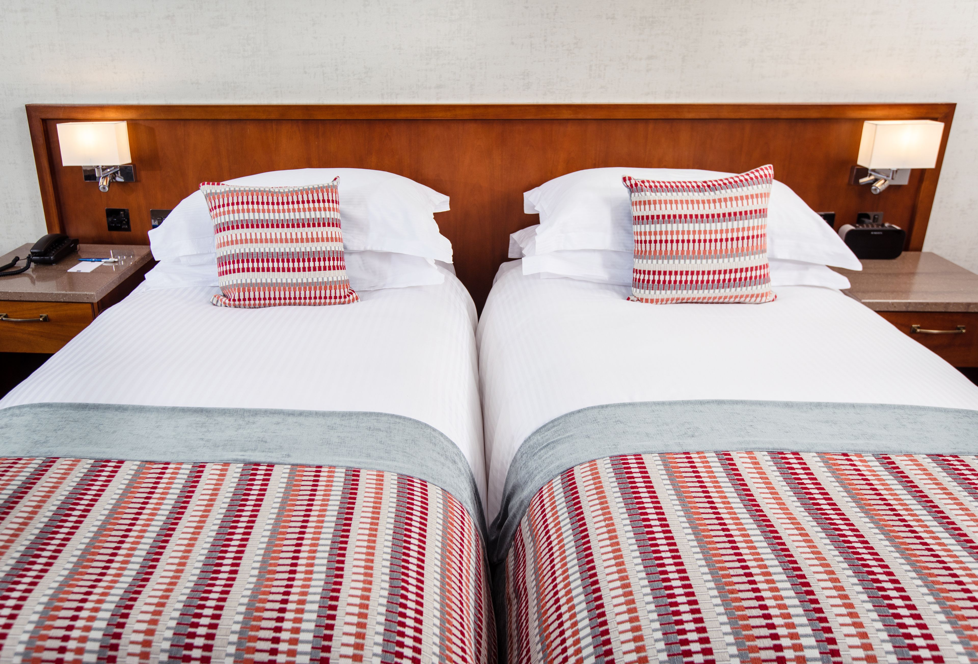 Una cama doble con un cojín de cuadros y una colcha estampada.