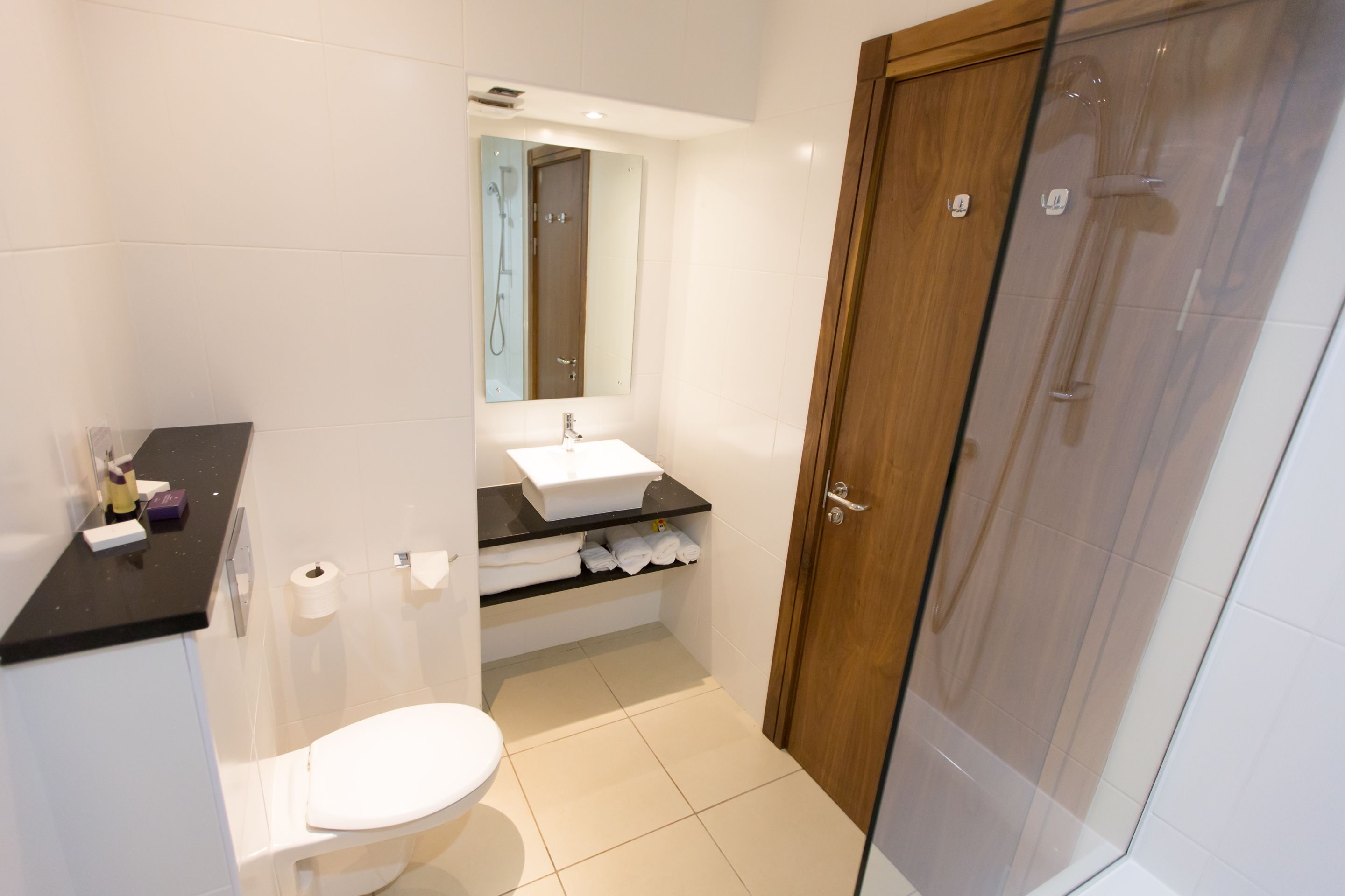 Un baño moderno con inodoro, lavamanos y cabina de ducha de vidrio.