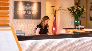A reception desk at the Stormont Hotel with a modern design, a nameplate, and a vase with flowers.
