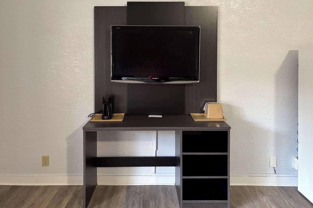 A modern entertainment unit with a flat-screen TV, a coffee maker, and a speaker.