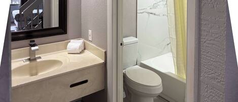 A bathroom with a sink, mirror, toilet, and bathtub.