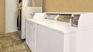 A laundry area with a washer and dryer, a coin-operated dryer, and a door to the left. - Days Inn & Suites by Wyndham Santa Rosa (Santa Rosa)