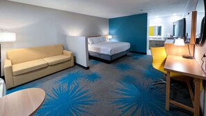 A hotel room with a bed, a sofa, a desk, and a bathroom visible in the background. - Days Inn & Suites by Wyndham Santa Rosa (Santa Rosa)