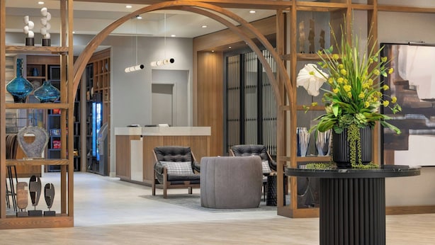 A modern interior with a reception desk, seating area, and decorative plants. - Renaissance Framingham Hotel & Conference Center (Framingham)