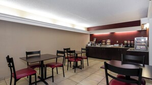 A restaurant with tables and chairs, a counter with food items, and a coffee machine. - Red Roof Inn Knoxville North - Merchants Drive (Knoxville)