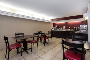 A restaurant with tables and chairs, a counter with food items, and a coffee machine. - Red Roof Inn Knoxville North - Merchants Drive (Knoxville)