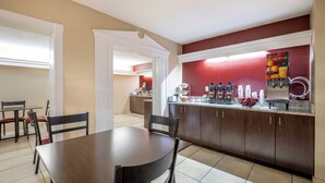 Un comedor con mesa y sillas, una cocina con cafetera, y una encimera con varios objetos.