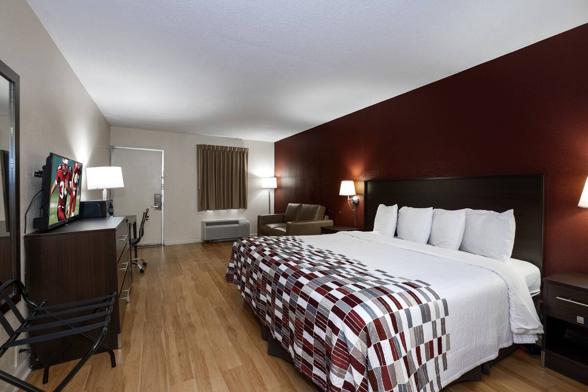 A hotel room with a large bed, a desk with a computer, a chair, and a TV.