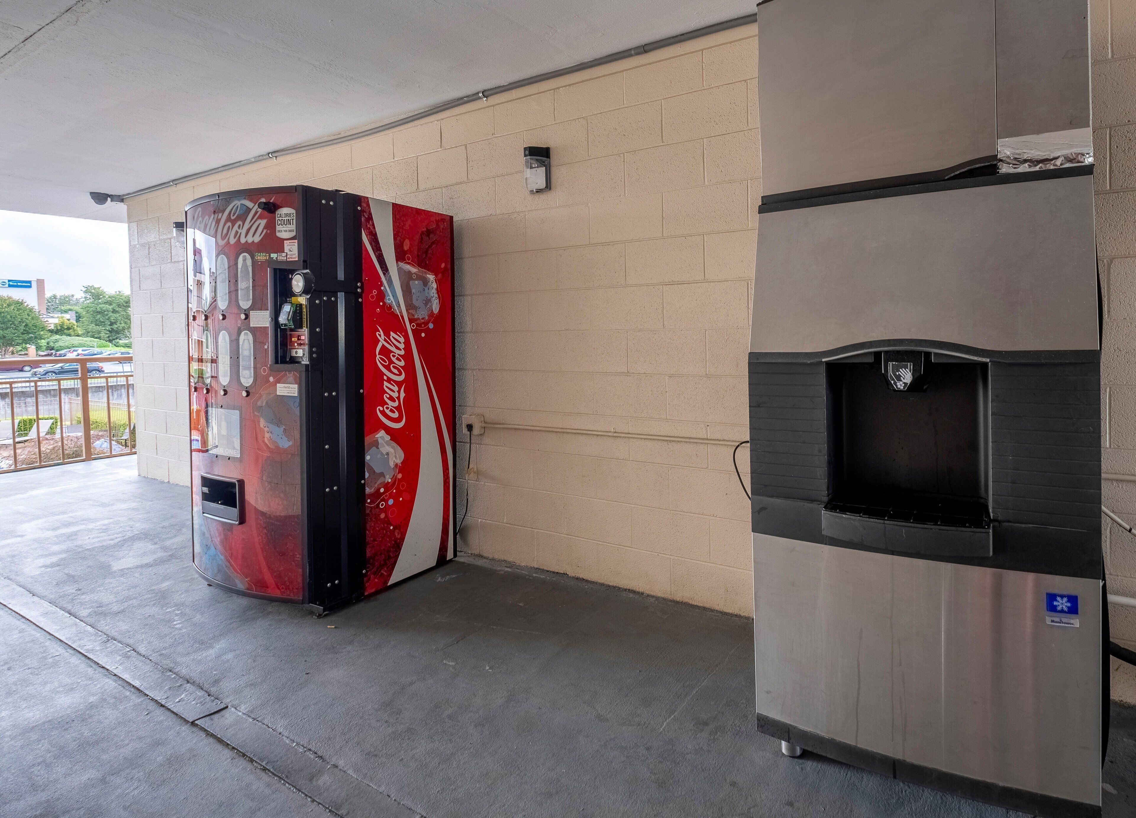 Una máquina expendedora de Coca-Cola y un refrigerador de acero inoxidable al aire libre.