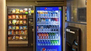 Een automaatruimte met snacks en drankautomaten, waaronder een koelkast voor Pepsi.