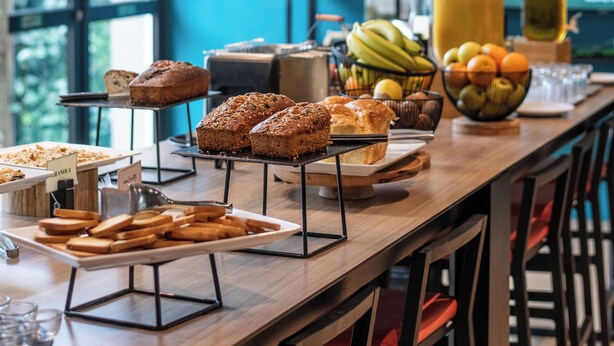 A breakfast buffet with various breads, pastries, and fruits.