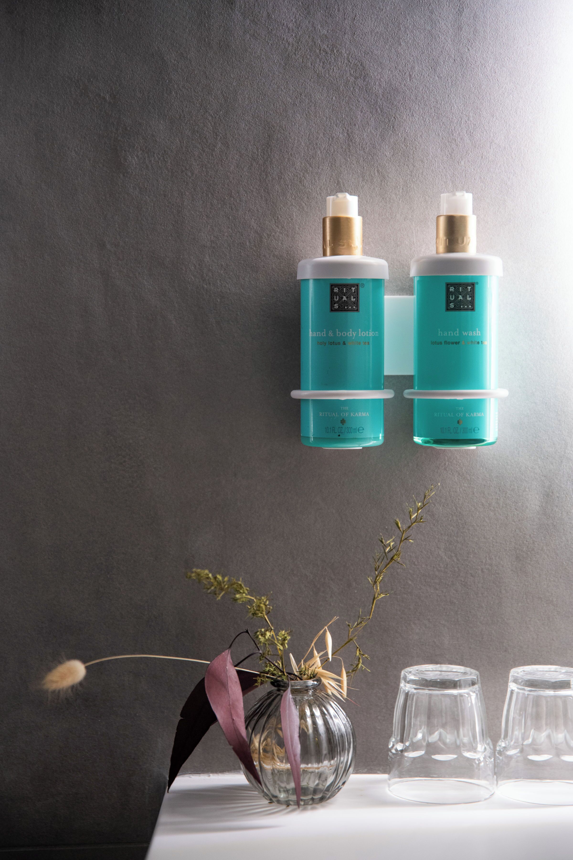 Un baño con dos botellas de loción corporal y dos de jabón de manos.