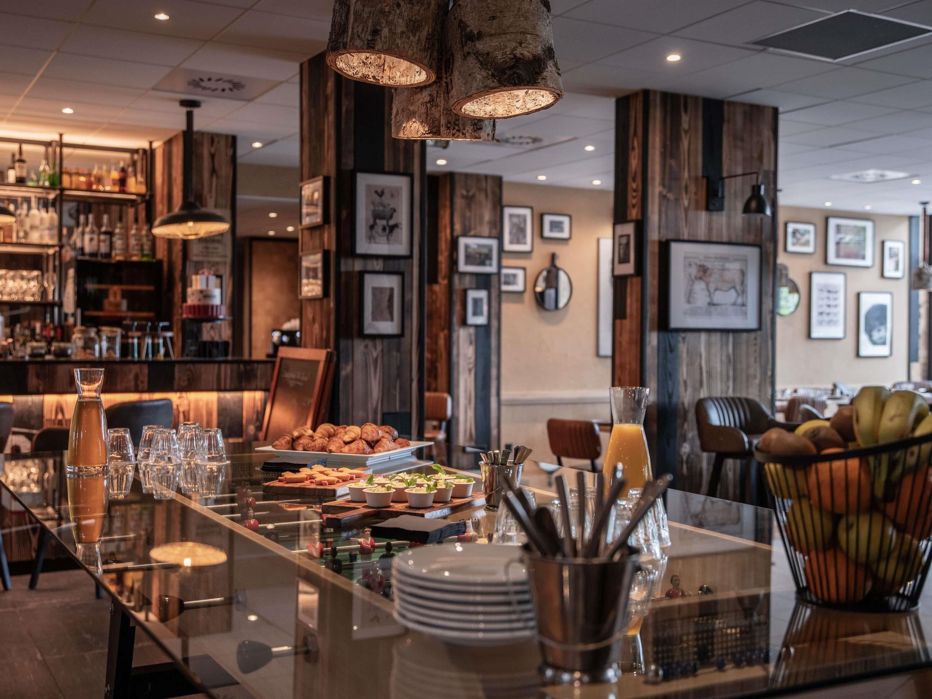 A restaurant with a long table set for dining, wooden walls, and framed pictures on the walls.