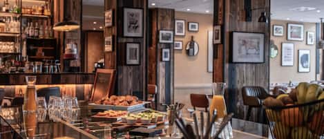 Un restaurante con una larga mesa dispuesta para comer, paredes de madera y cuadros en las paredes.