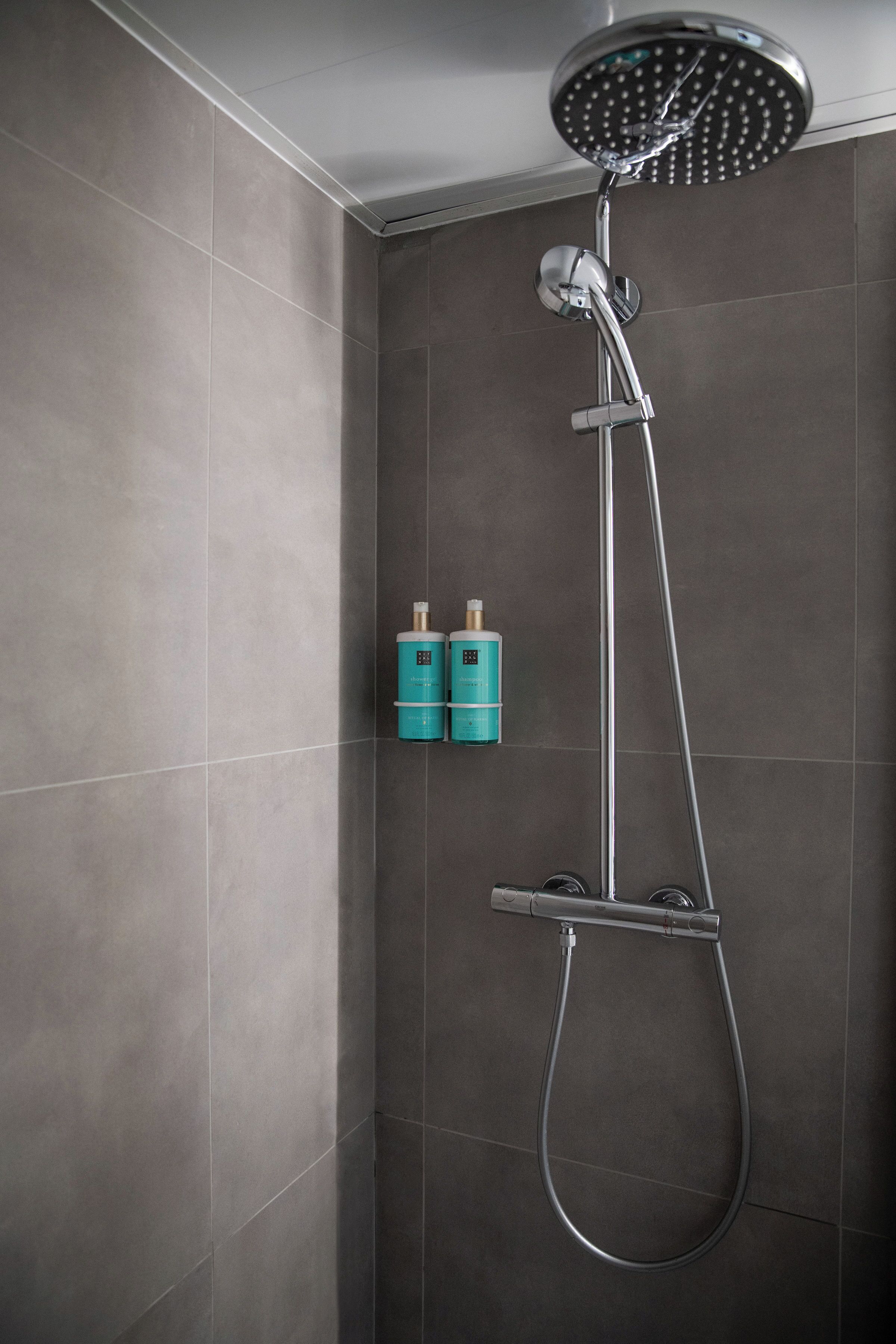 A shower with a handheld showerhead and a wall-mounted faucet.