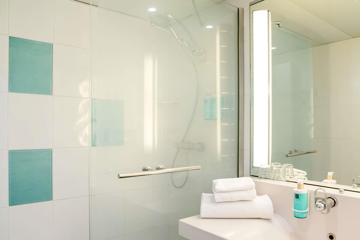 A modern bathroom with a glass shower enclosure, a white sink, and a mirror.