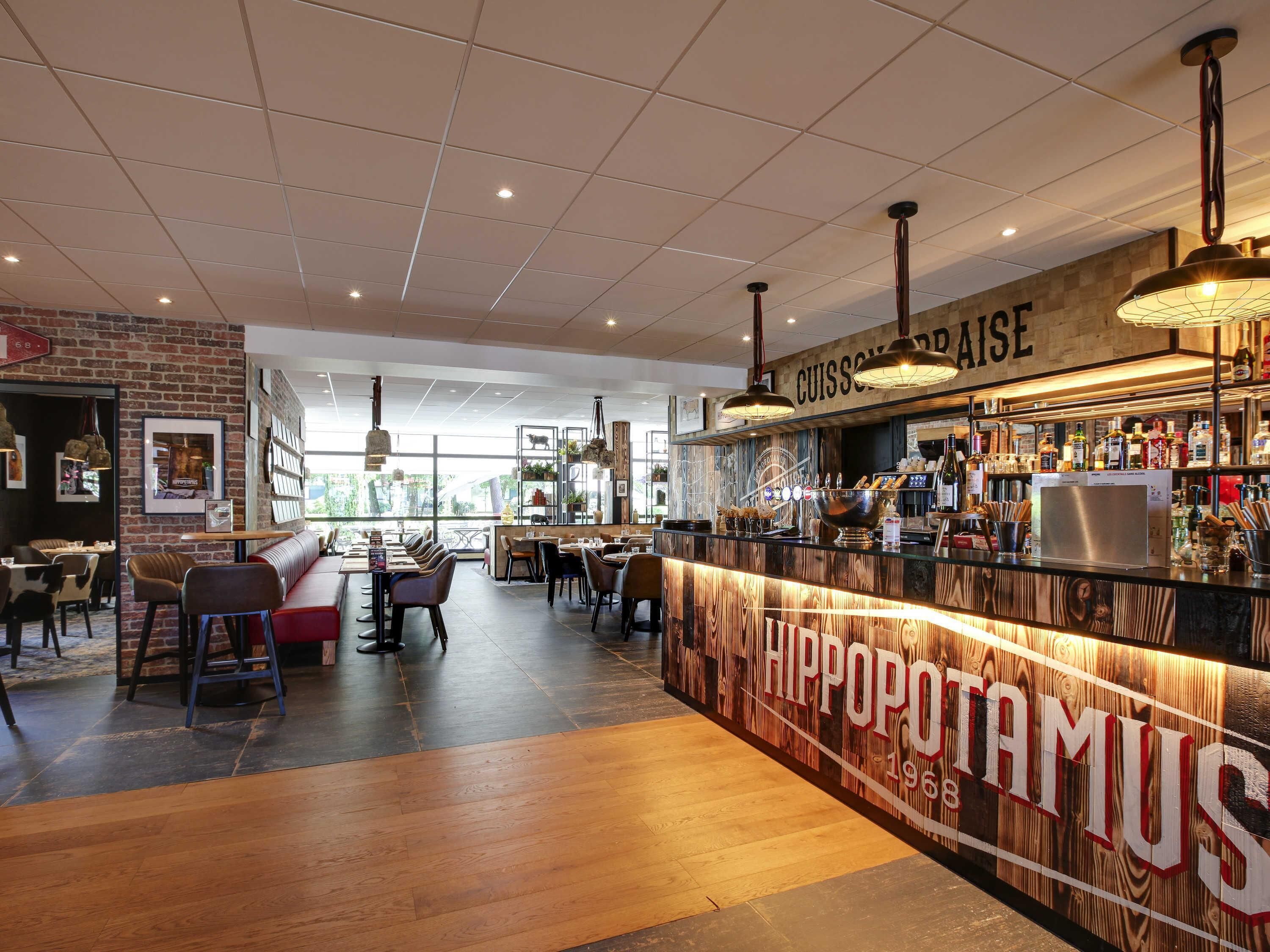 A restaurant interior with a bar area, wooden flooring, and a brick wall.