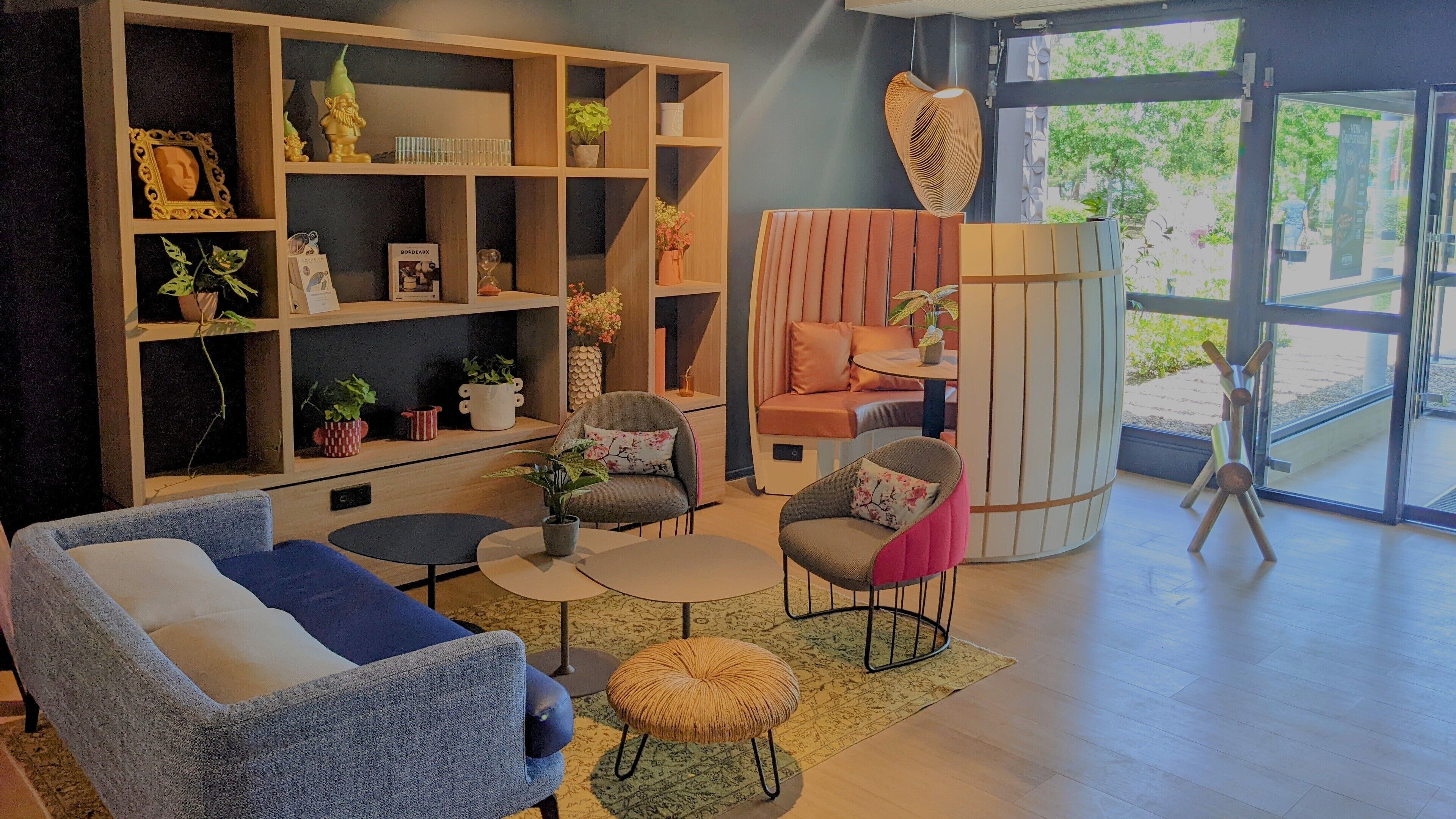 Un salon moderne comprenant un canapé, des fauteuils, une table basse et une bibliothèque remplie d’objets décoratifs.