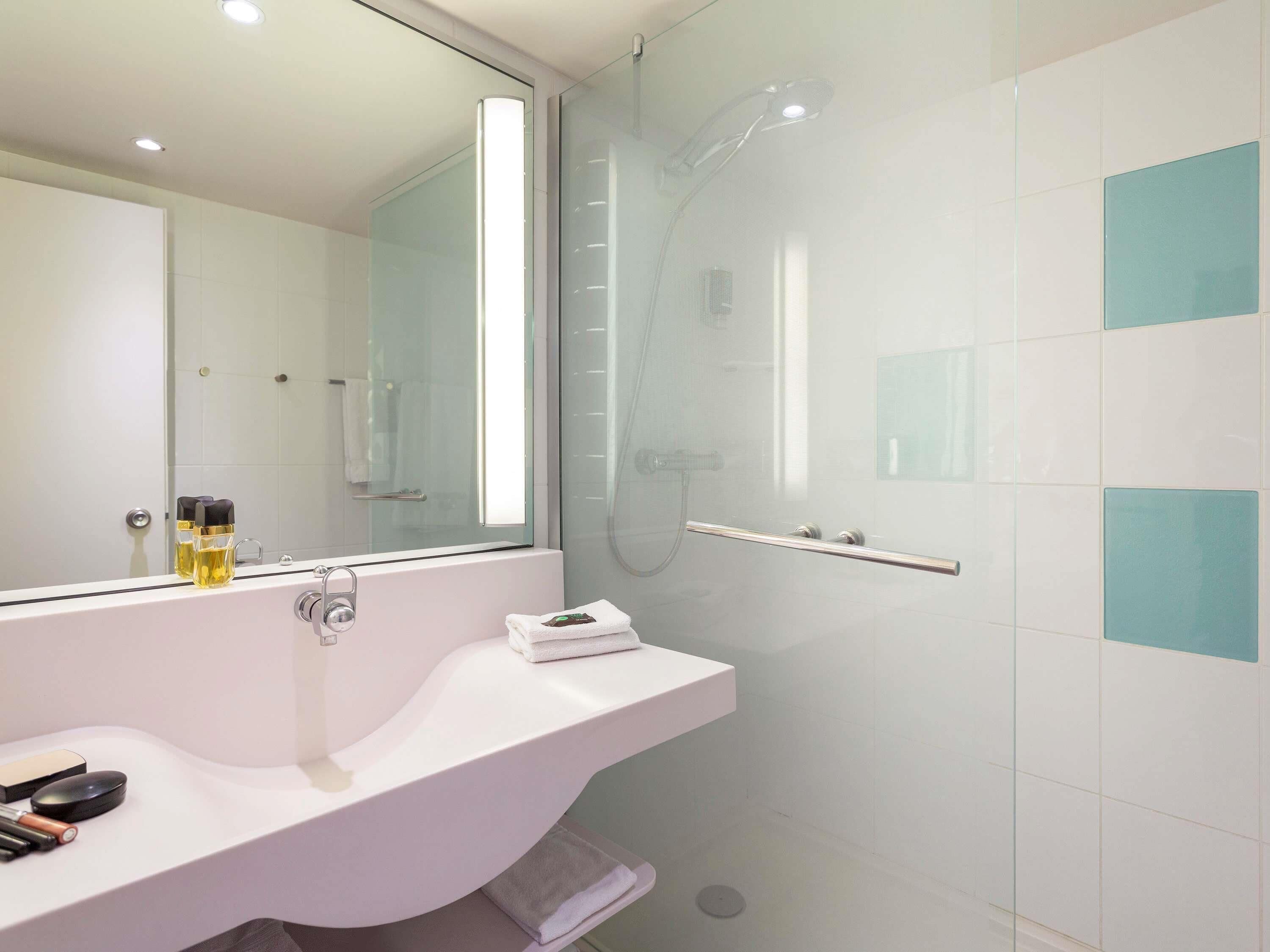 A modern bathroom with a glass shower enclosure, a white sink, and a mirror.