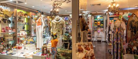 Una boutique exhibe una variedad de ropa y accesorios, incluyendo sombreros, bolsos y joyería.