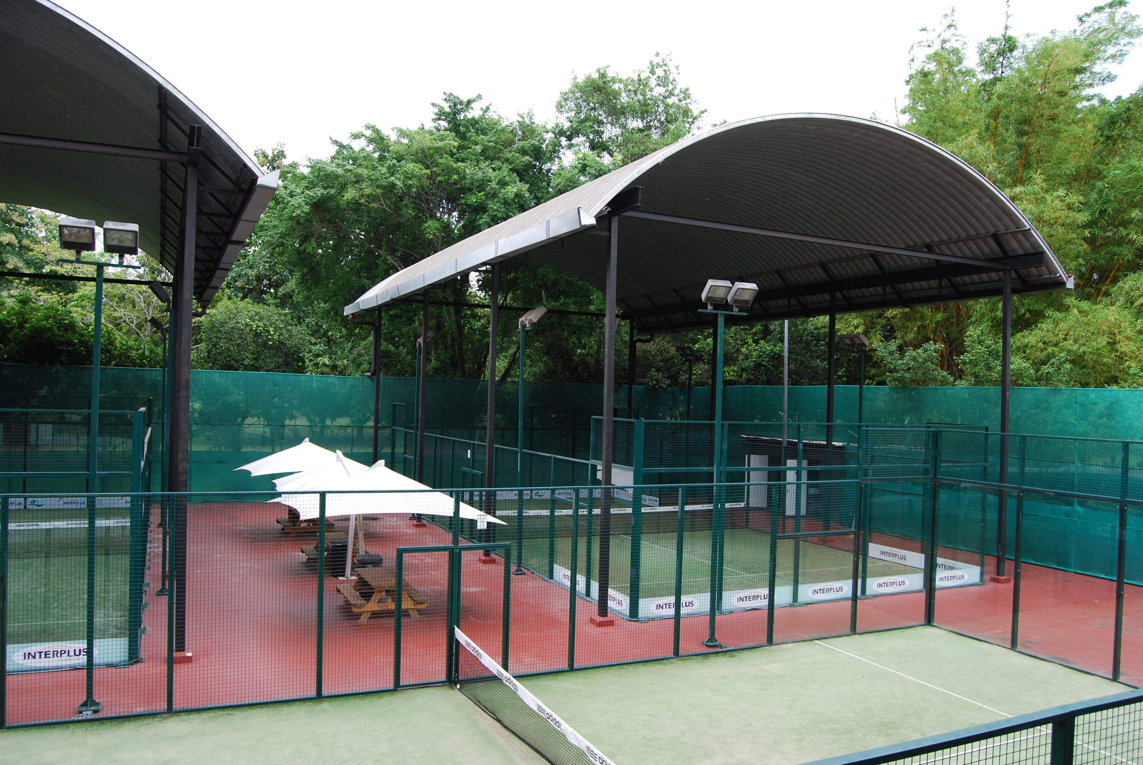 Pista de tenis interior con zona de asientos techada y red.