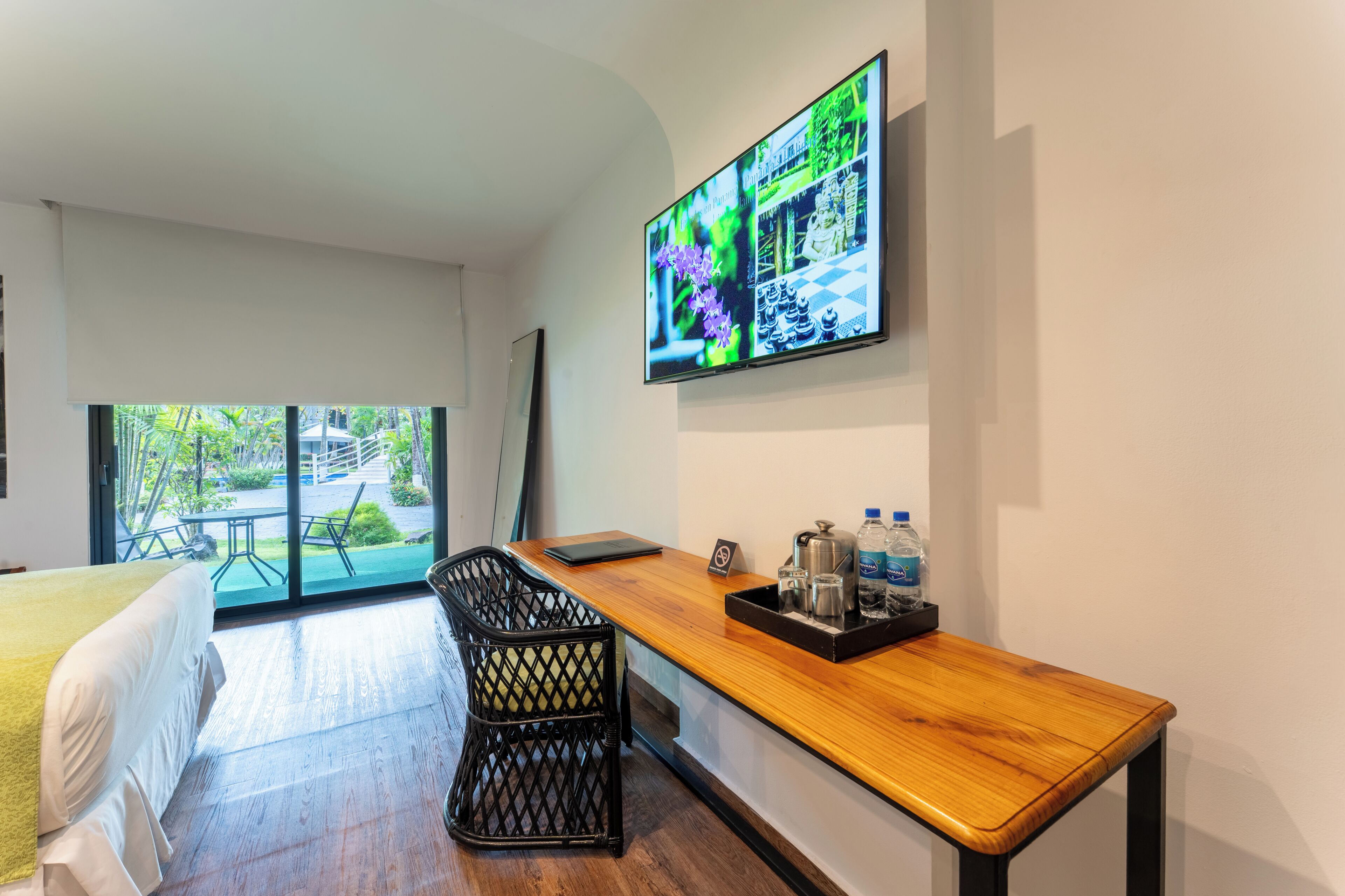 Ein Hotelzimmer mit Bett, Schreibtisch mit Laptop, Fernseher an der Wand und Blick ins Freie.