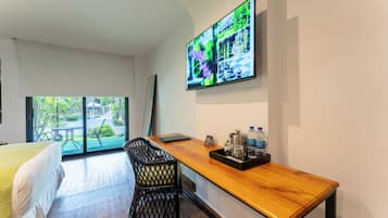 Ein Hotelzimmer mit Bett, Schreibtisch mit Laptop, Fernseher an der Wand und Blick ins Freie.