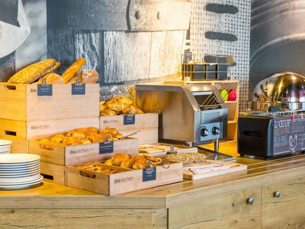 A bakery display with various baked goods in wooden boxes labeled with names like 'Palmenblanc' and 'Croissant de Tour.'