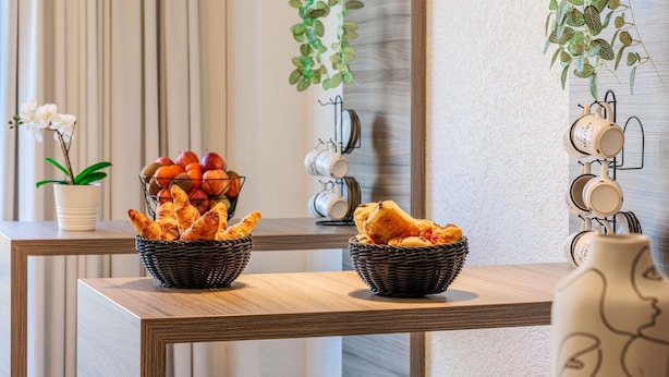 Una mesa de madera con dos cestas de mimbre que contienen pan y un bol de fruta.