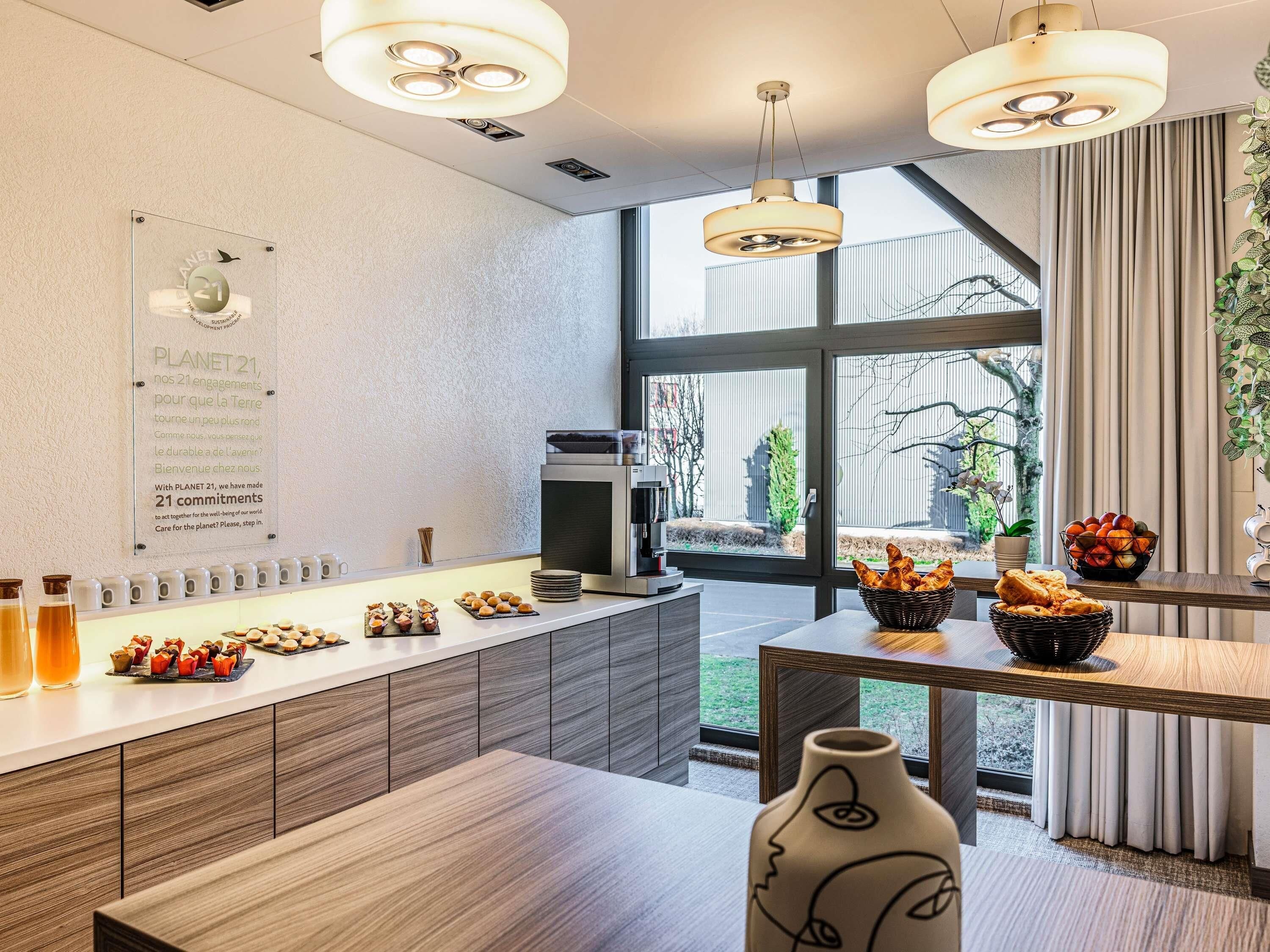 Une cuisine moderne dotée d’un grand îlot central, d’une machine à café et offrant une vue sur l’extérieur.