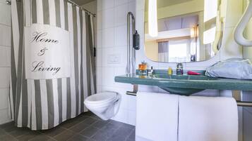 A bathroom with a striped shower curtain, a toilet, a sink with a mirror, and a towel rack.