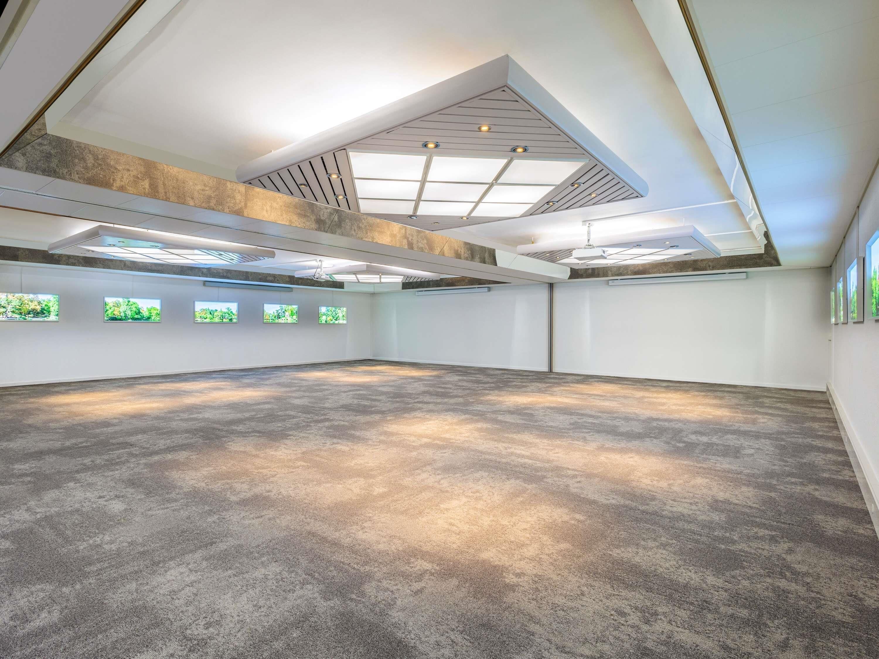 Una habitación amplia con techo alto, tragaluces y suelo de hormigón.
