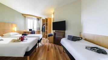 Une chambre d’hôtel avec deux lits, une télévision, une armoire et une fenêtre.