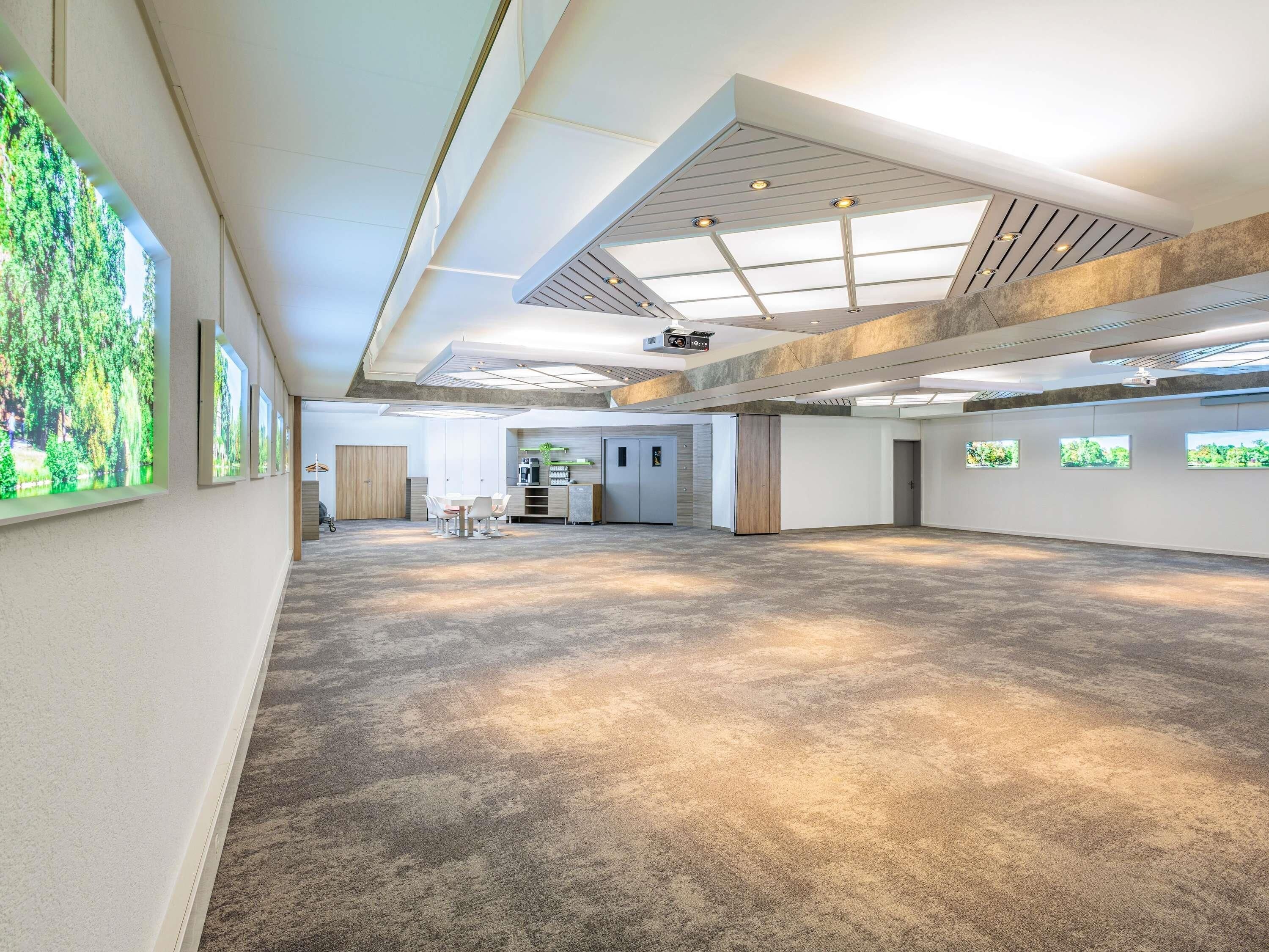 Een ruime binnenruimte met een hoge plafond, inbouwverlichting en een centraal zithoek.