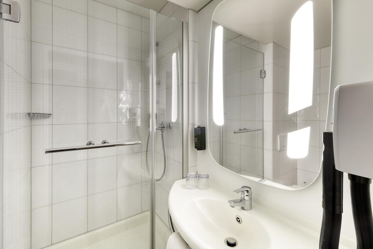A modern bathroom with a glass shower enclosure, a white sink, and a large mirror.