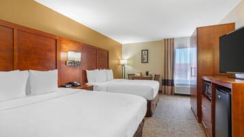 A hotel room with two beds, a desk, a television, and a minibar.