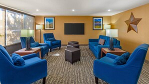 Habitación de hotel con sillones azules, un televisor de pantalla plana y un adorno con forma de estrella en la pared.